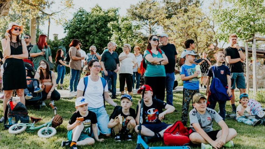 A diverse group of people enjoying a sunny day at an outdoor community event in a park setting.